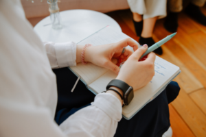 notebook sitting in lap with hands taking notes